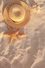 Photo of Flat lay composition with starfish and straw hat on sandy beach. Space for text