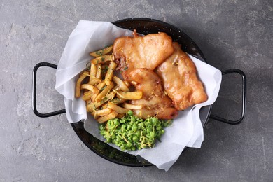 Photo of Tasty fish, chips and peas on grey table, top view