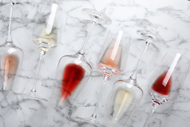 Glasses with different wine on marble background, flat lay