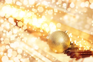 Image of Beautiful golden bauble and fairy lights on piano. Christmas music. Bokeh effect