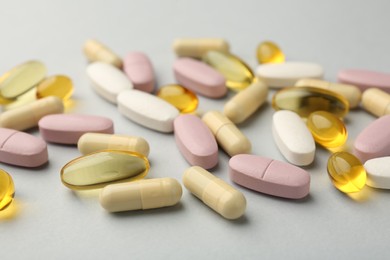 Different vitamin pills on light grey background, closeup. Health supplement