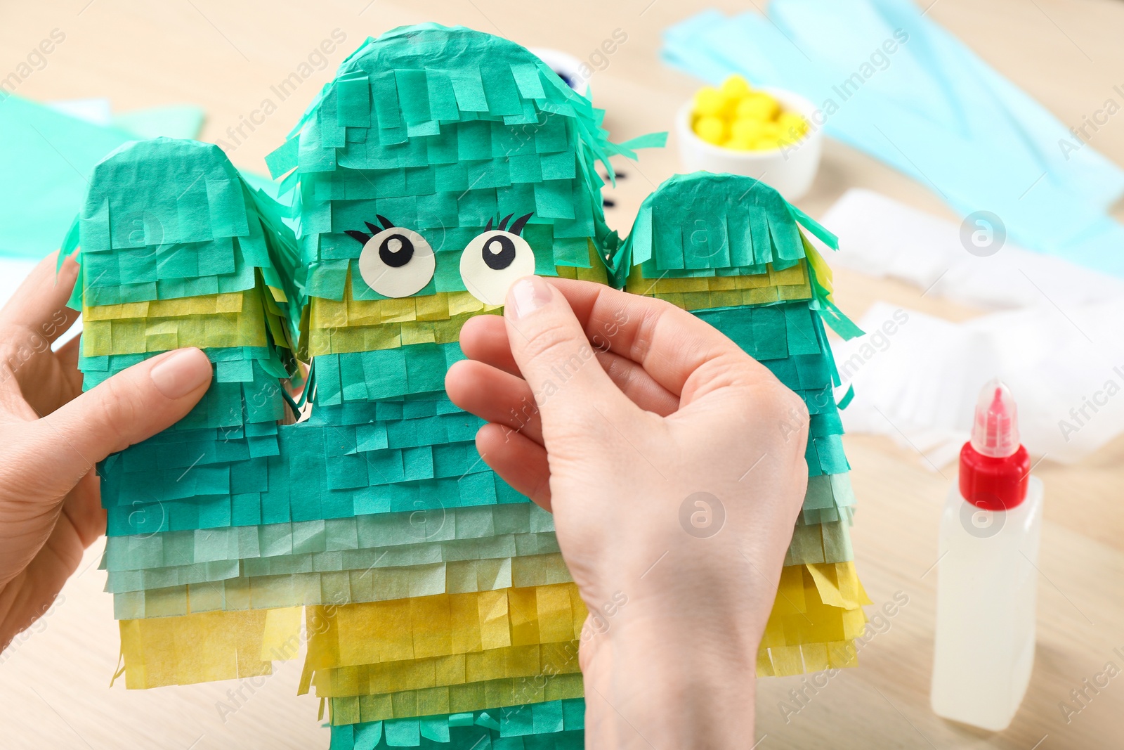 Photo of Woman decorating cardboard cactus at table, closeup. Pinata diy