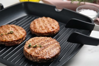 Photo of Grill pan with tasty fried hamburger patties on white table