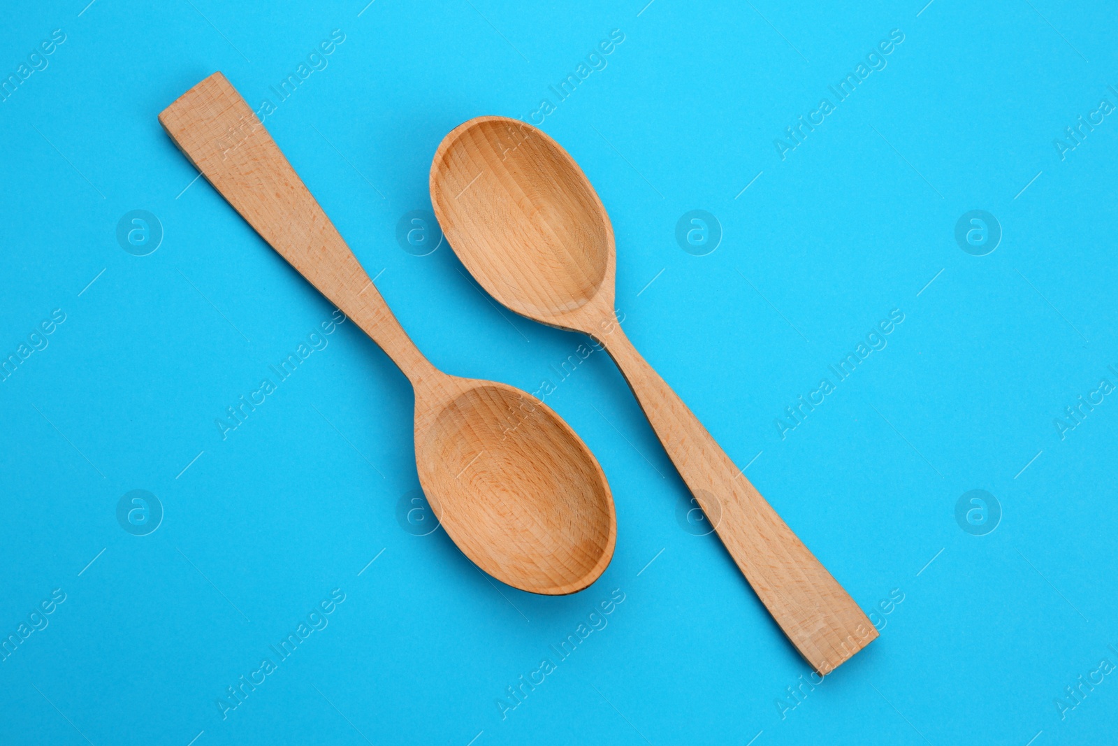 Photo of Clean empty wooden spoons on blue background, top view