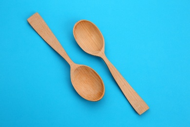 Clean empty wooden spoons on blue background, top view