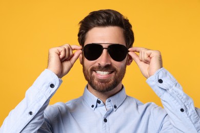 Photo of Portrait of smiling bearded man with stylish sunglasses against orange background