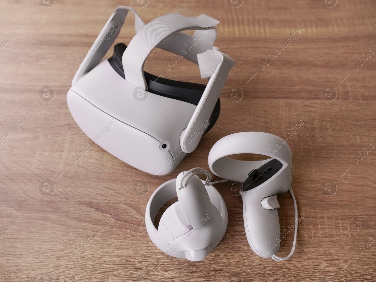 Photo of Modern virtual reality headset and controllers on wooden table, above view