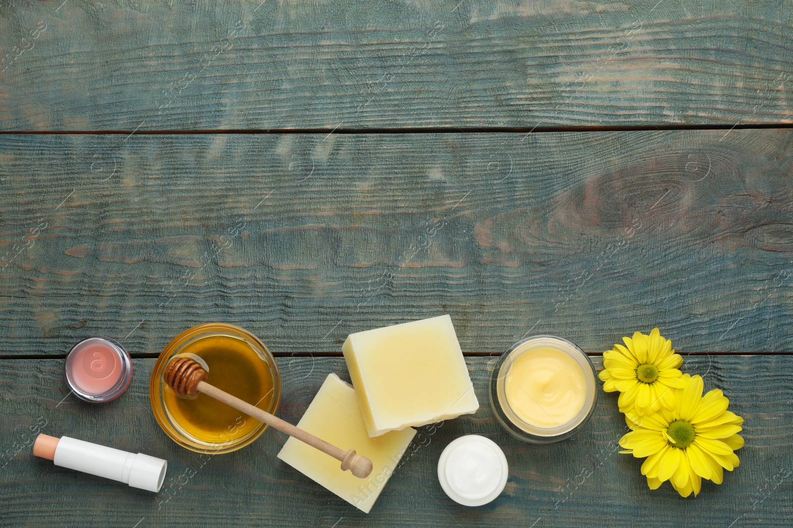 Photo of Flat lay composition with beeswax and cosmetic products on blue wooden table. Space for text