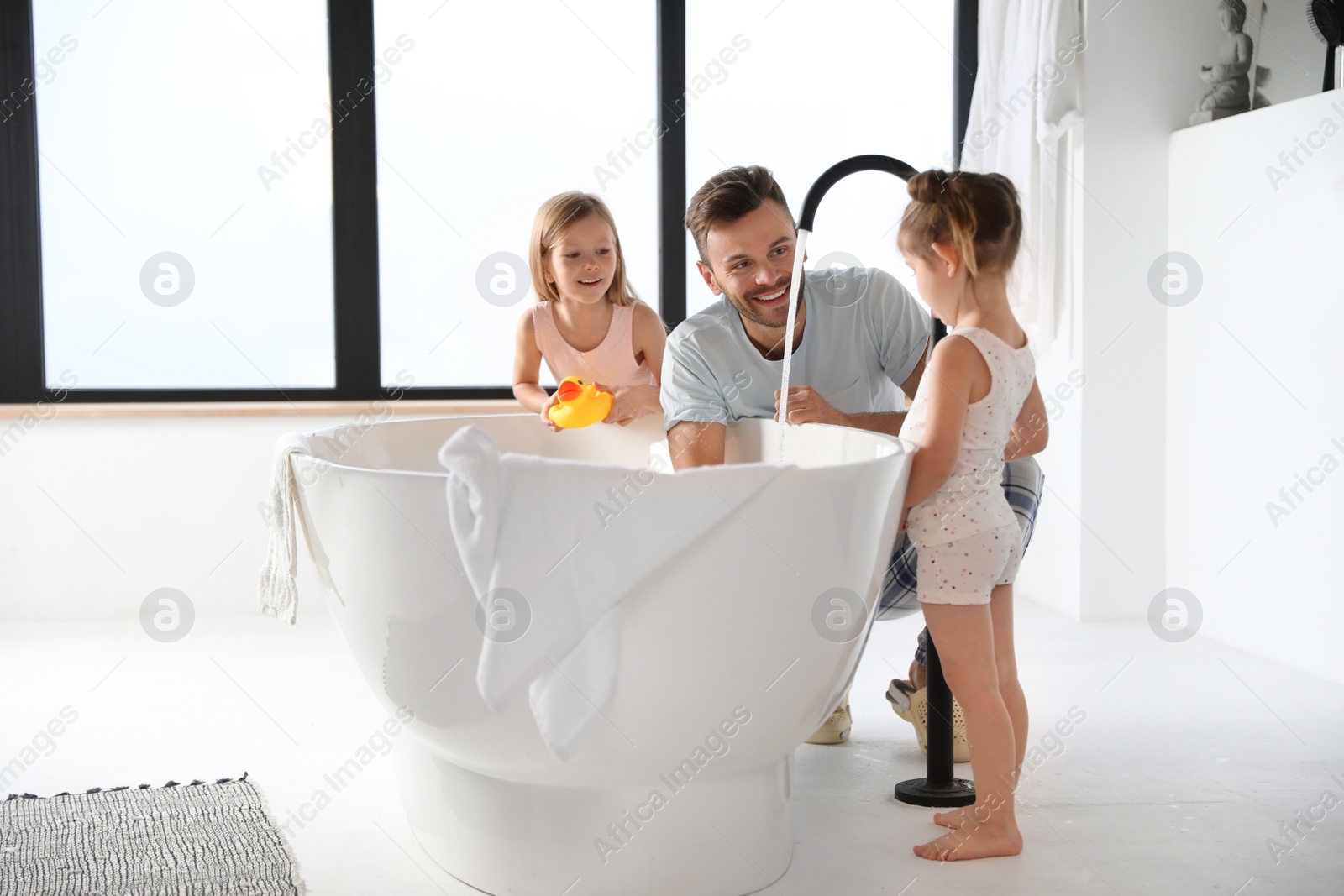 Photo of Young father with little daughters in bathroom