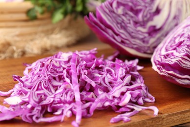 Photo of Heap of shredded fresh red cabbage on wooden table, closeup