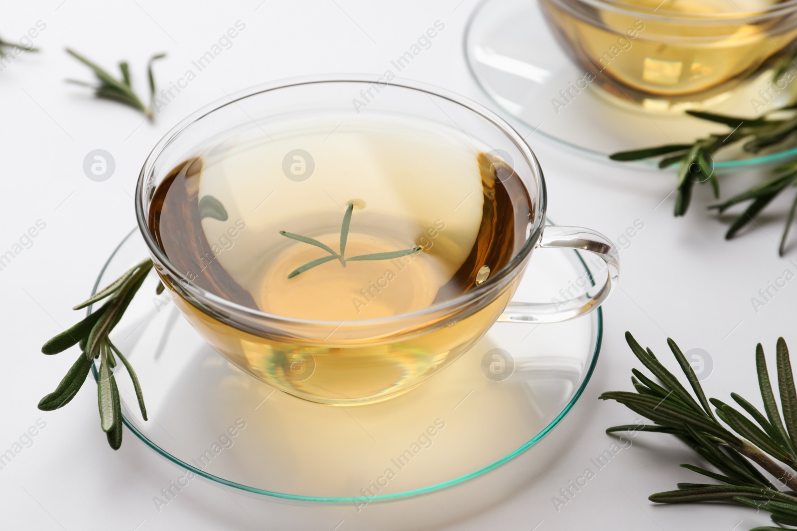 Photo of Cup of aromatic herbal tea with rosemary on white table