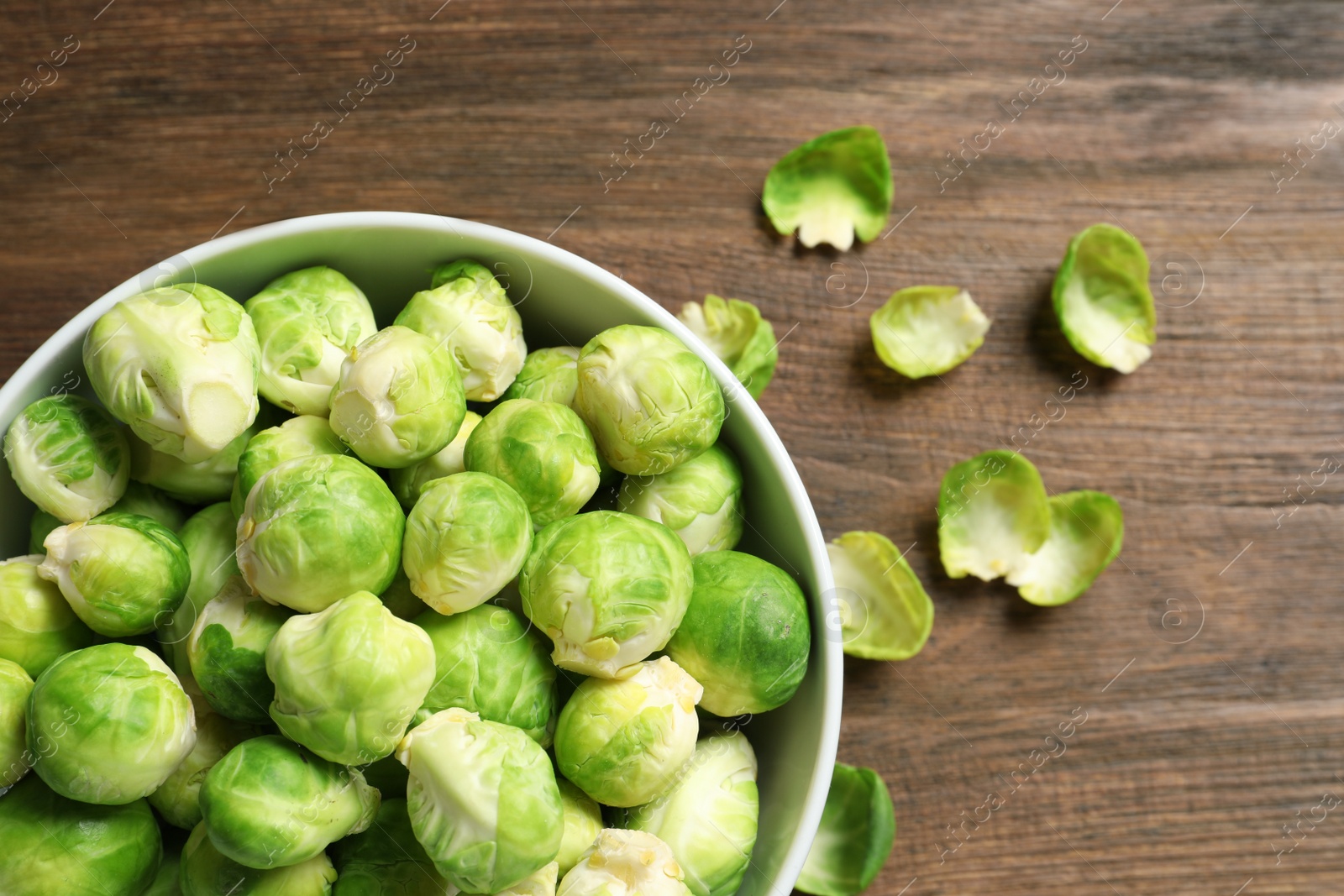 Photo of Bowl of fresh Brussels sprouts on wooden background, top view with space for text