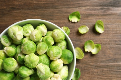 Photo of Bowl of fresh Brussels sprouts on wooden background, top view with space for text