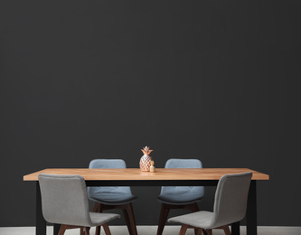 Photo of Modern table with decorative pineapples near black wall