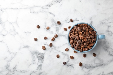 Cup with coffee beans on marble background