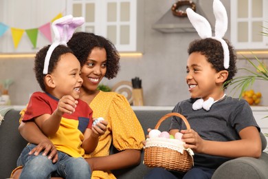 Photo of Happy African American mother and her cute children with Easter eggs in kitchen