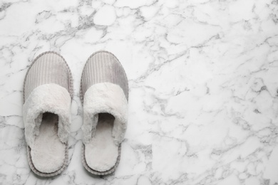 Pair of soft slippers on white marble background, flat lay. Space for text