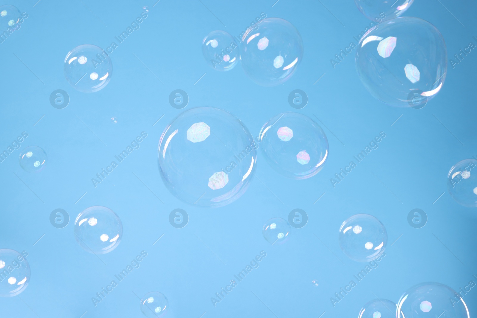 Photo of Many beautiful soap bubbles on light blue background. Space for text