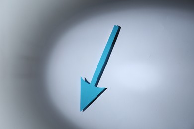 Photo of Light blue paper arrow on white background, top view