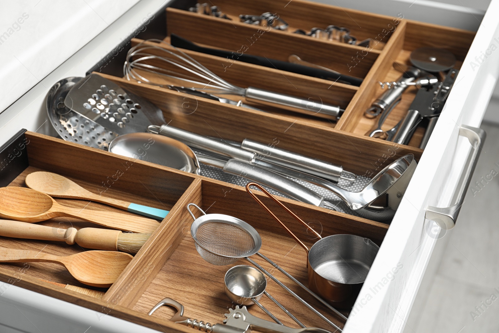 Photo of Different utensils in open desk drawer indoors, closeup