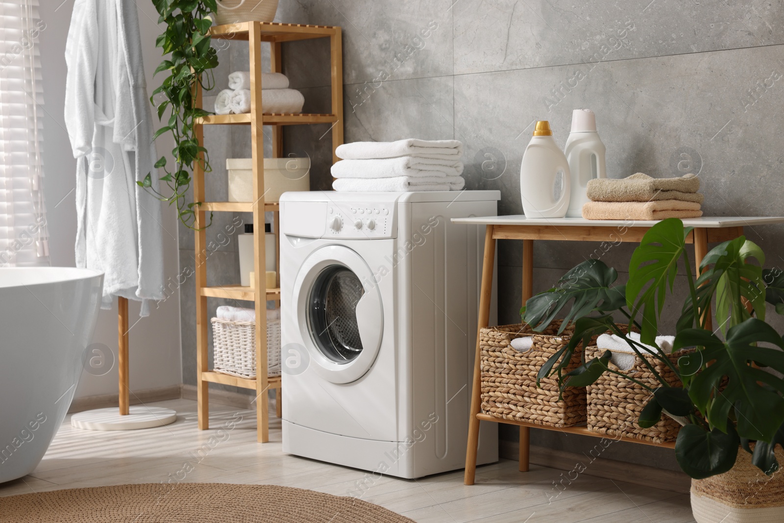 Photo of Clean towels, washing machine, plants and deterrents in bathroom