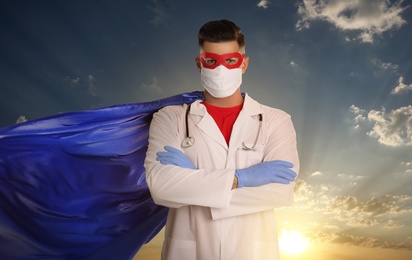 Image of Medical workers fighting with dangerous diseases. Doctor dressed as superhero posing against sky