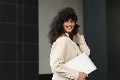 Happy young woman holding modern laptop outdoors