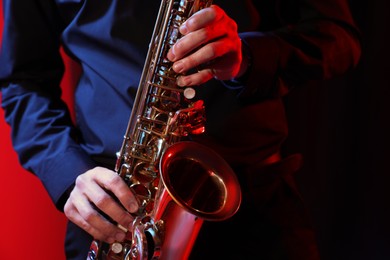 Photo of Man with saxophone on dark background, closeup
