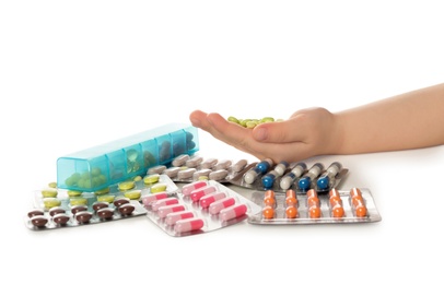 Photo of Little child with many different pills on white background, closeup. Danger of medicament intoxication