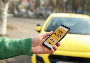 Photo of Man ordering taxi with smartphone on city street, closeup