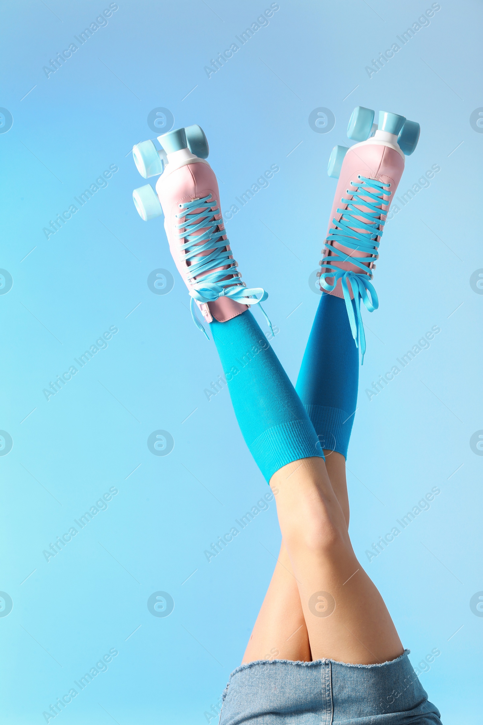 Photo of Woman with vintage roller skates on color background, closeup