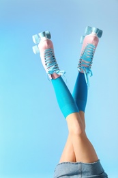 Photo of Woman with vintage roller skates on color background, closeup