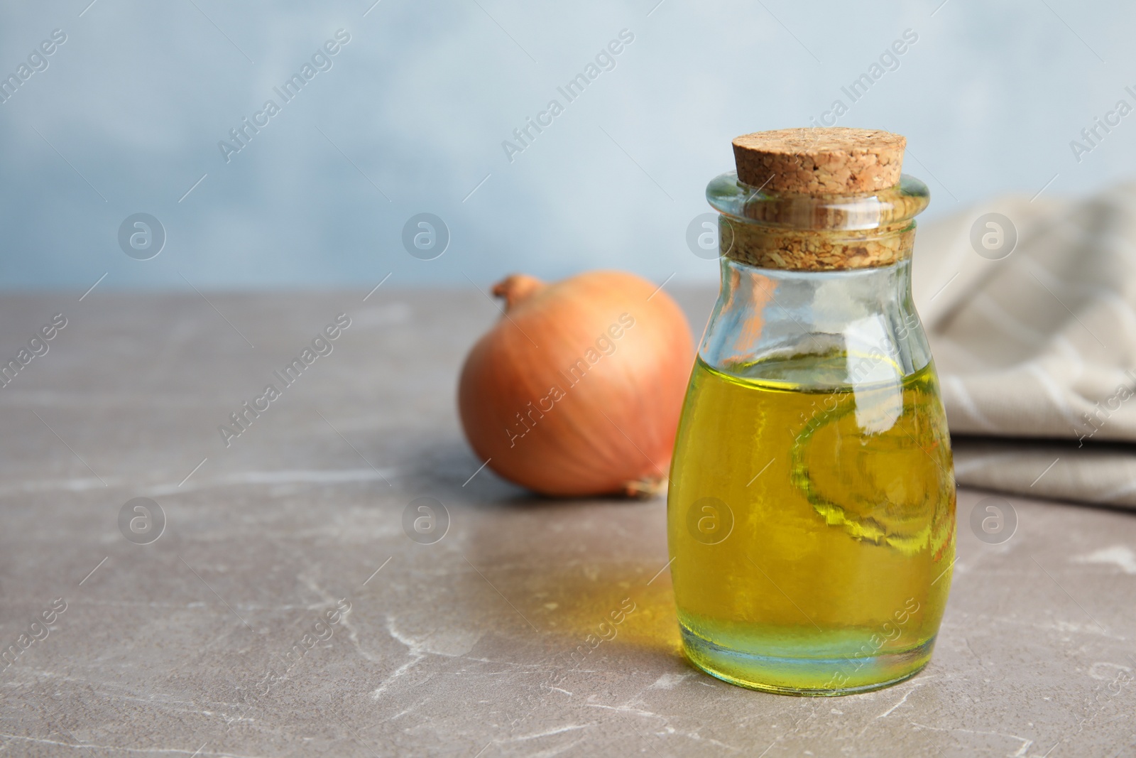 Photo of Glass bottle of onion syrup and fresh vegetable on table. Space for text