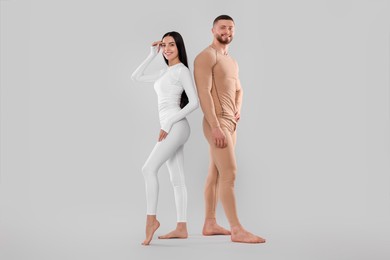 Photo of Man and woman in warm thermal underwear on light background