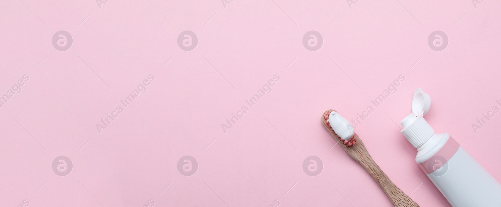 Image of Tube and brush with toothpaste on light pink background, flat lay with space for text. Banner design