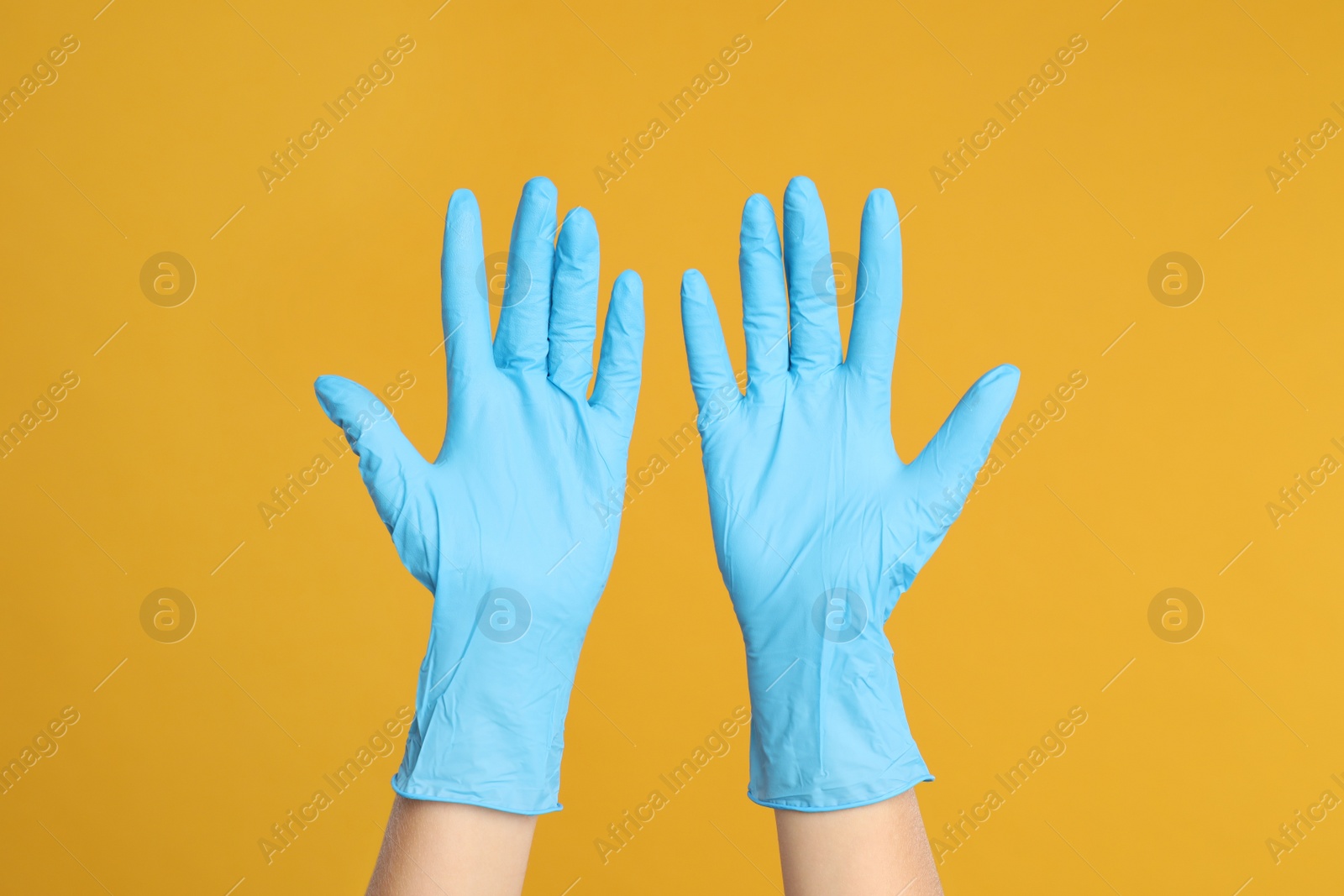 Photo of Doctor wearing medical gloves on yellow background, closeup