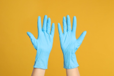 Photo of Doctor wearing medical gloves on yellow background, closeup