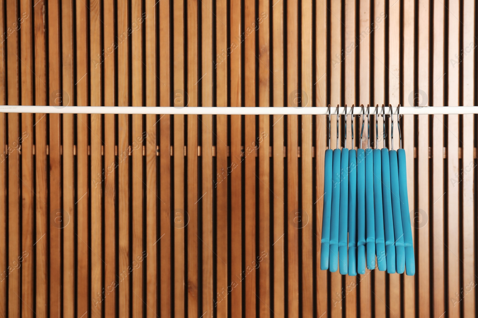 Photo of Empty hangers on rail against wooden background, space for text