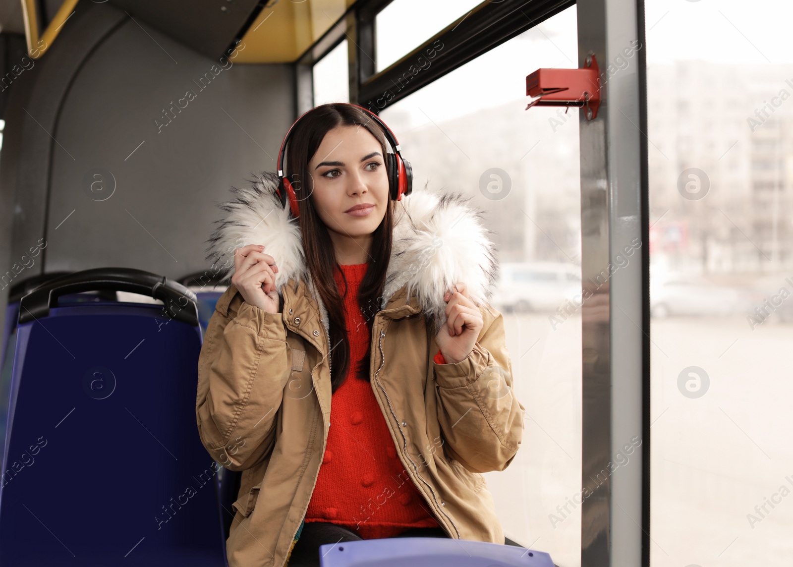 Photo of Young woman listening to music with headphones in public transport