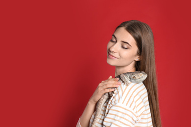 Photo of Woman holding bearded lizard on red background. Exotic pet