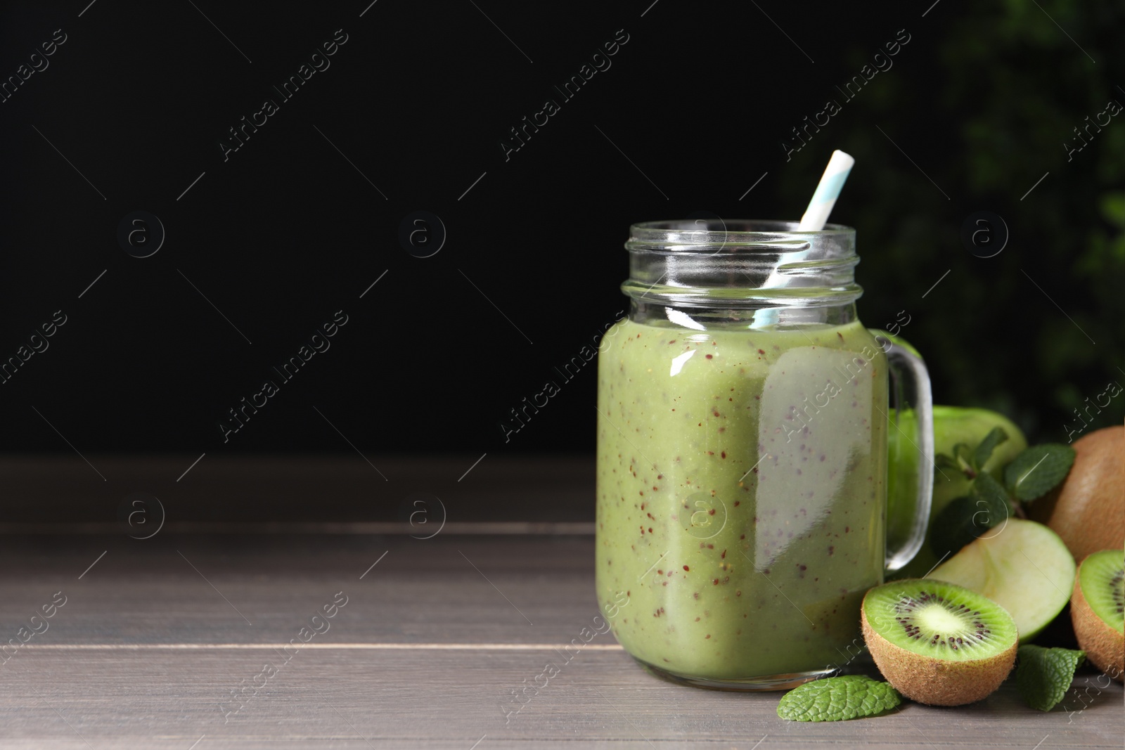 Photo of Delicious kiwi smoothie and ingredients on wooden table. Space for text