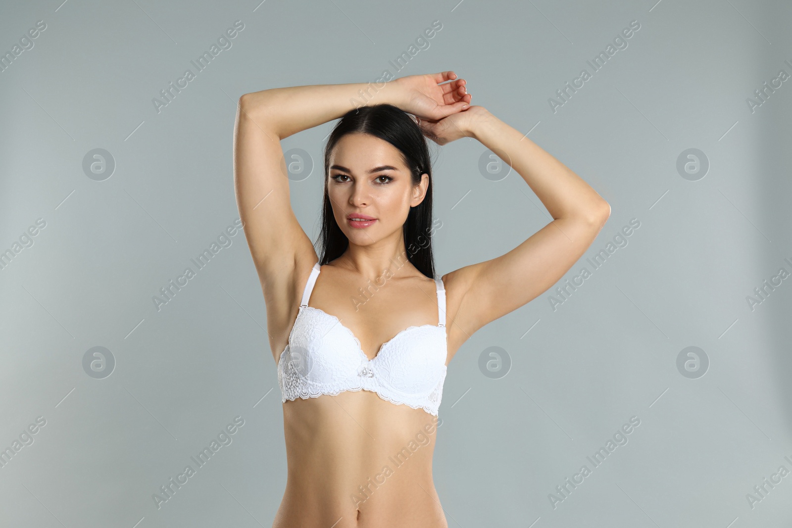 Photo of Beautiful young woman in white underwear on grey background