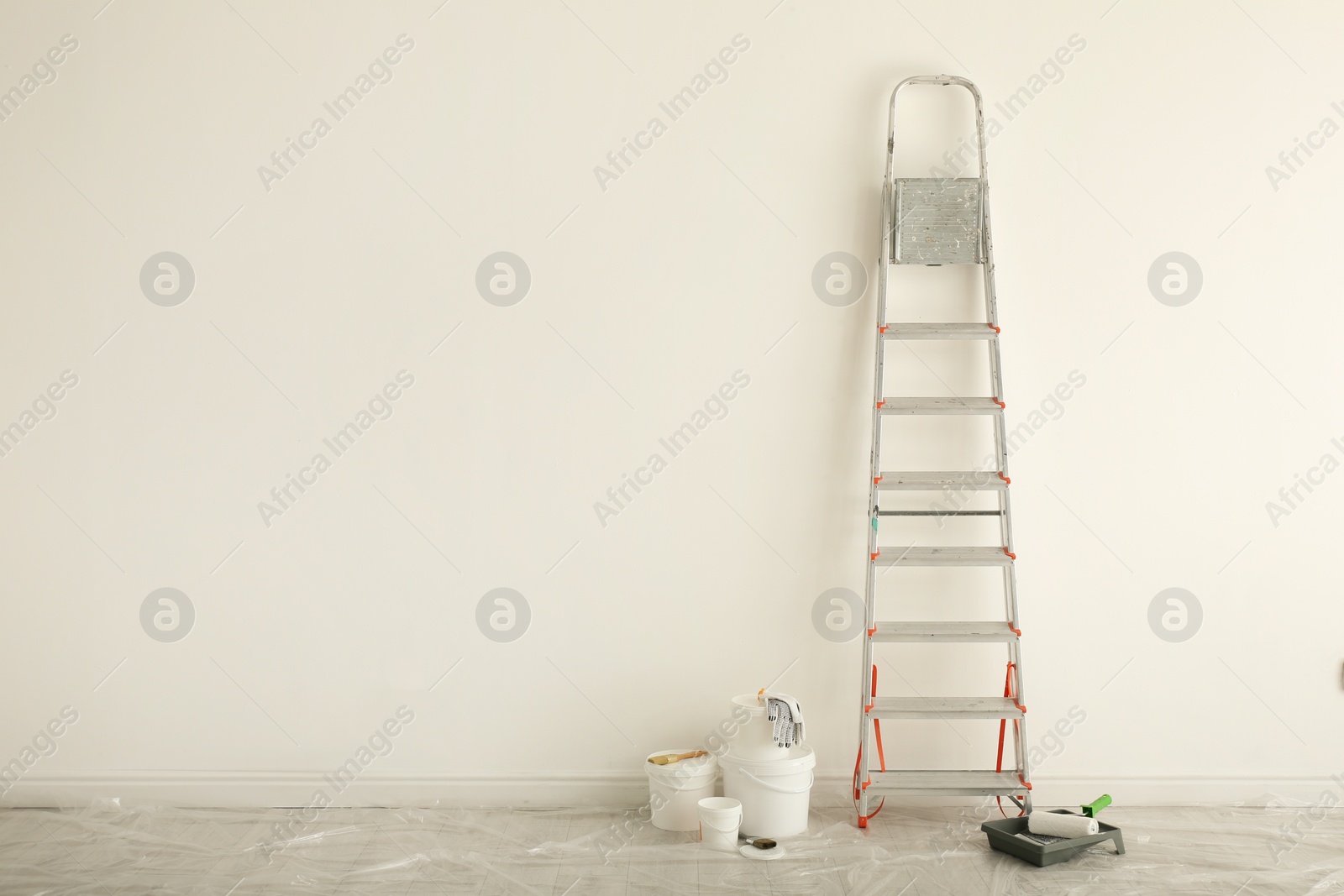 Photo of Stepladder and different tools near wall in room, space for text. Interior renovation