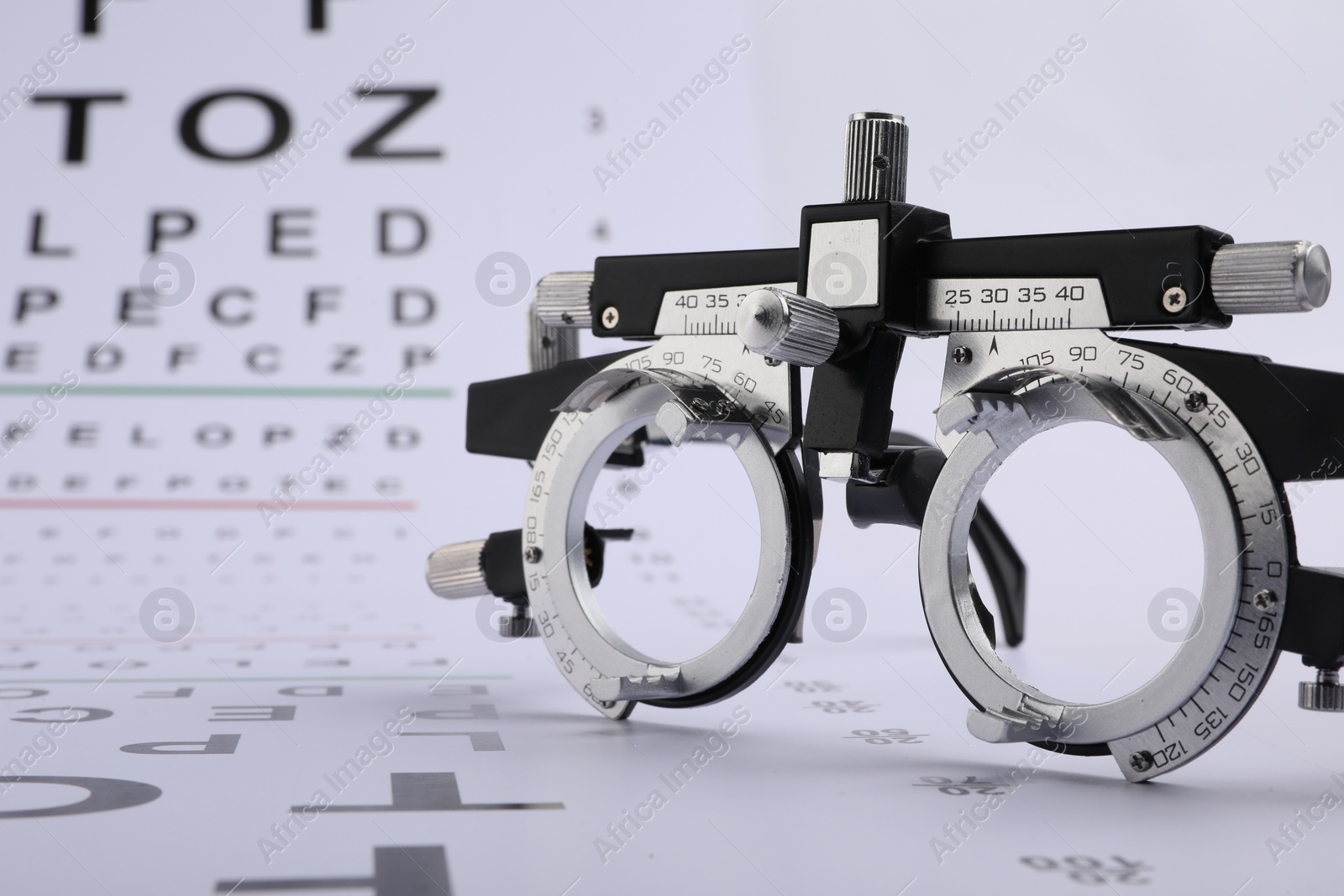 Photo of Vision test chart and trial frame on white background, closeup