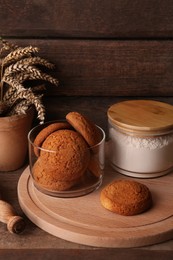 Cookies, flour and wheat spikes on wooden table