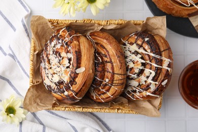 Photo of Delicious rolls with toppings and almond on white tiled table, flat lay. Sweet buns