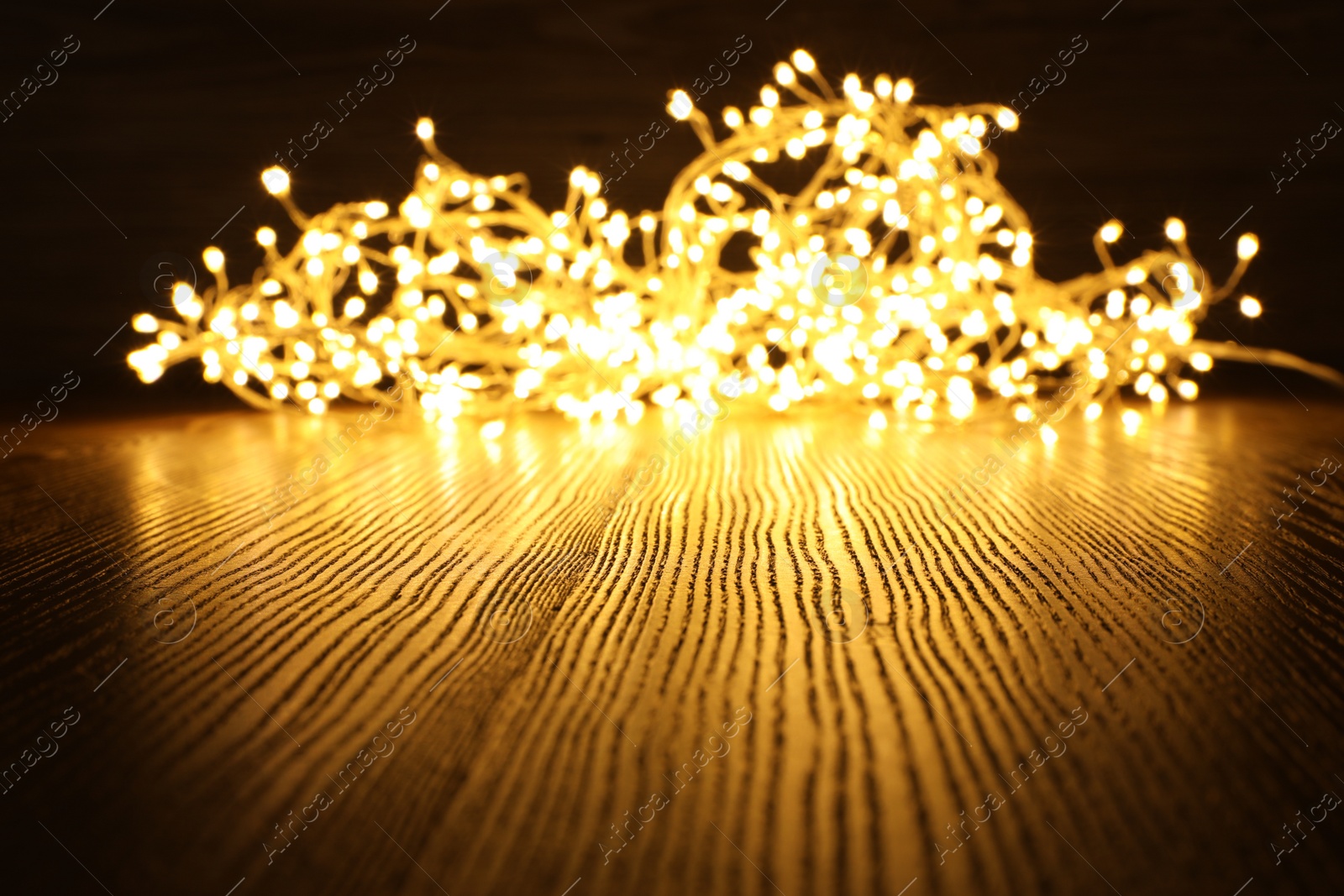 Photo of Beautiful glowing Christmas lights on wooden table. Space for text