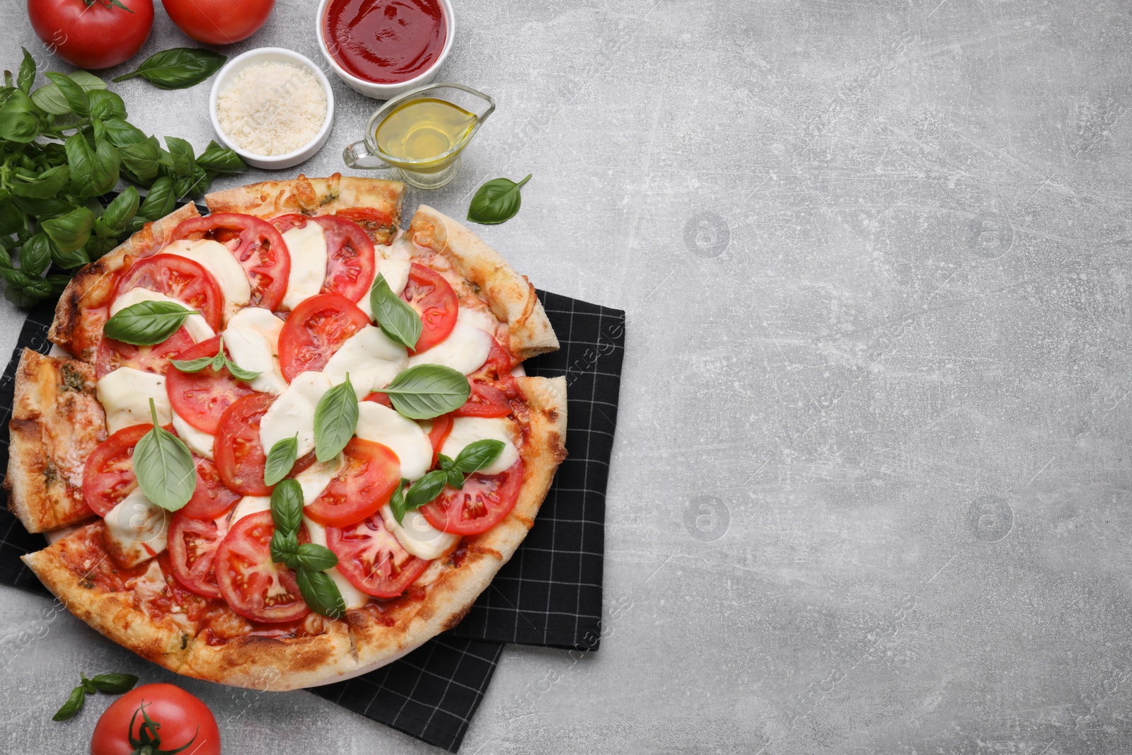 Photo of Delicious Caprese pizza with tomatoes, mozzarella and basil served on light grey table, flat lay. Space for text