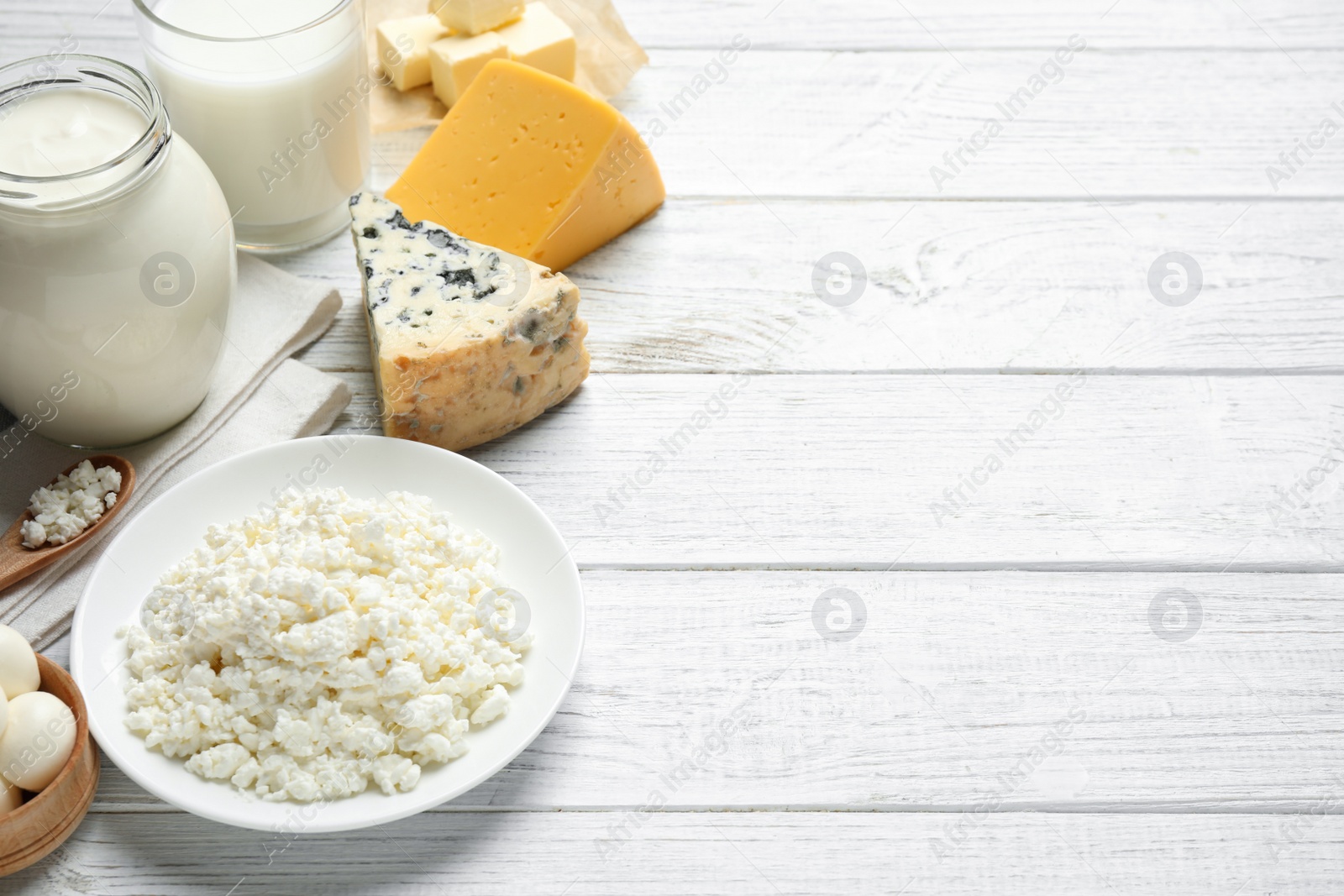 Photo of Different dairy products on white wooden table. Space for text