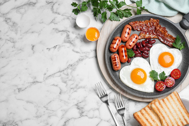 Photo of Delicious breakfast with heart shaped fried eggs and  sausages on white marble table, flat lay. Space for text